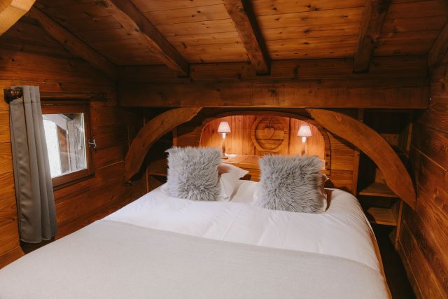 Chambre cosy avec lit double et lampe de chevet au fond, décoration chaleureuse.
