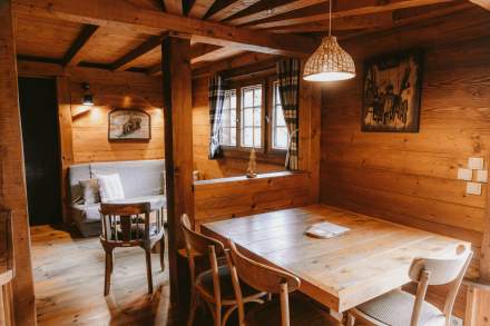 Salon dans un chalet en bois avec canapé, chaise, TV, fenêtre et décoration, et salle à manger