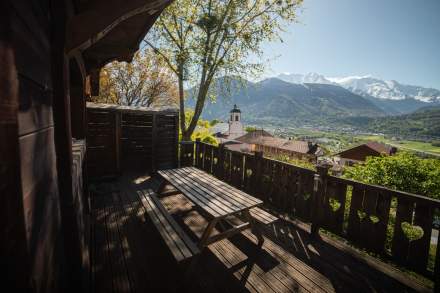 Terrasse d'un chalet avec vue sur les montagnes enneigée et la verdure