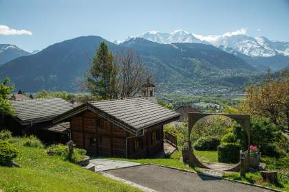 Chalets vu de derrière, verdure et montagne enneigée au loin