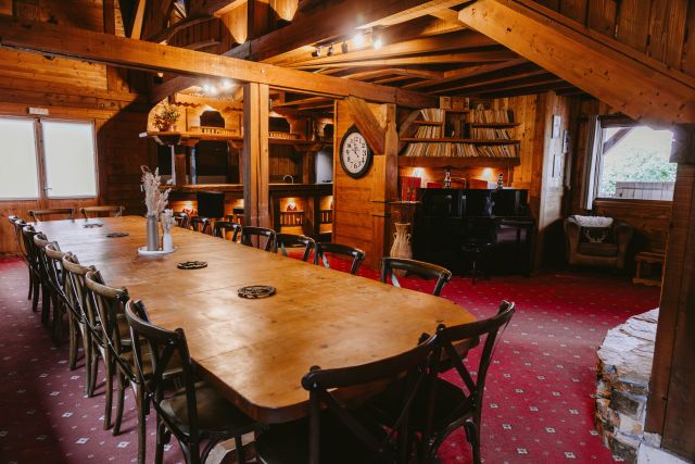 Salle à manger spacieuse dans un chalet en bois avec grande table convivale pouvant accueillir environ 20 personnes.