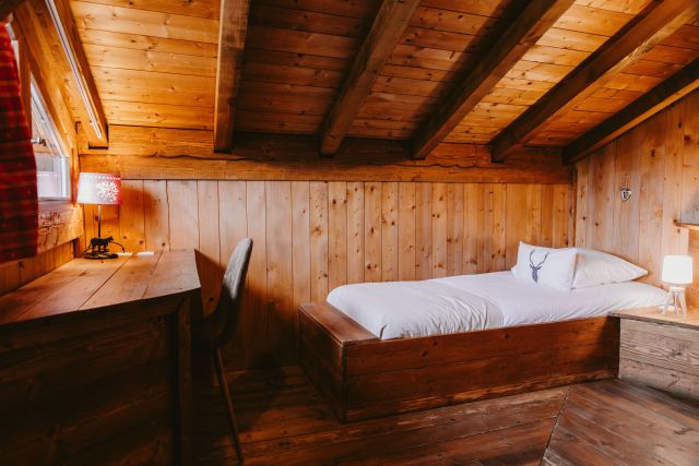 Chambre avec lit simple dans un chalet en bois, ambiace cosy et chaleureuse.
