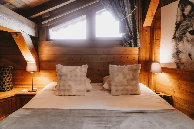 Chambre confortable avec lit double dans un chalet en bois, ambiance chaleureuse et cosy.